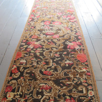 Karabagh Runner with European Design - This stunning runner is a fine example of a small group of carpets and runners produced by the Caucasian weavers in the Karabagh region which reflect a European aesthetic, but with the angularity and dramatic colouring one associates with the Caucasus. At the end of the 19th century, the presence of substantial numbers of Russian military and bureaucratic personnel in the Caucasus influenced the styles of rugs and carpets that were being woven in the villages and workshops. This runner with its design of roses and dramatic golden swags is clearly a reference to French decorative styles so popular with the Russians. The brown background which has corroded in places gives the design a relief or three-dimensional effect in places. Most examples I have seen of this group have a black or dark blue background, The light brown background of our piece coupled with the pale greens, pinks and golds, makes the overall appearance lighter and less formal than other examples.  Note also the simple repeating neo-classical border, another clear reference to the European ancestry of this piece. Professionally cleaned and with only some minor restoration to the brown background, this piece has has survived the generations well, and is now ready for immediate use. Image of Karabagh Runner with European Design